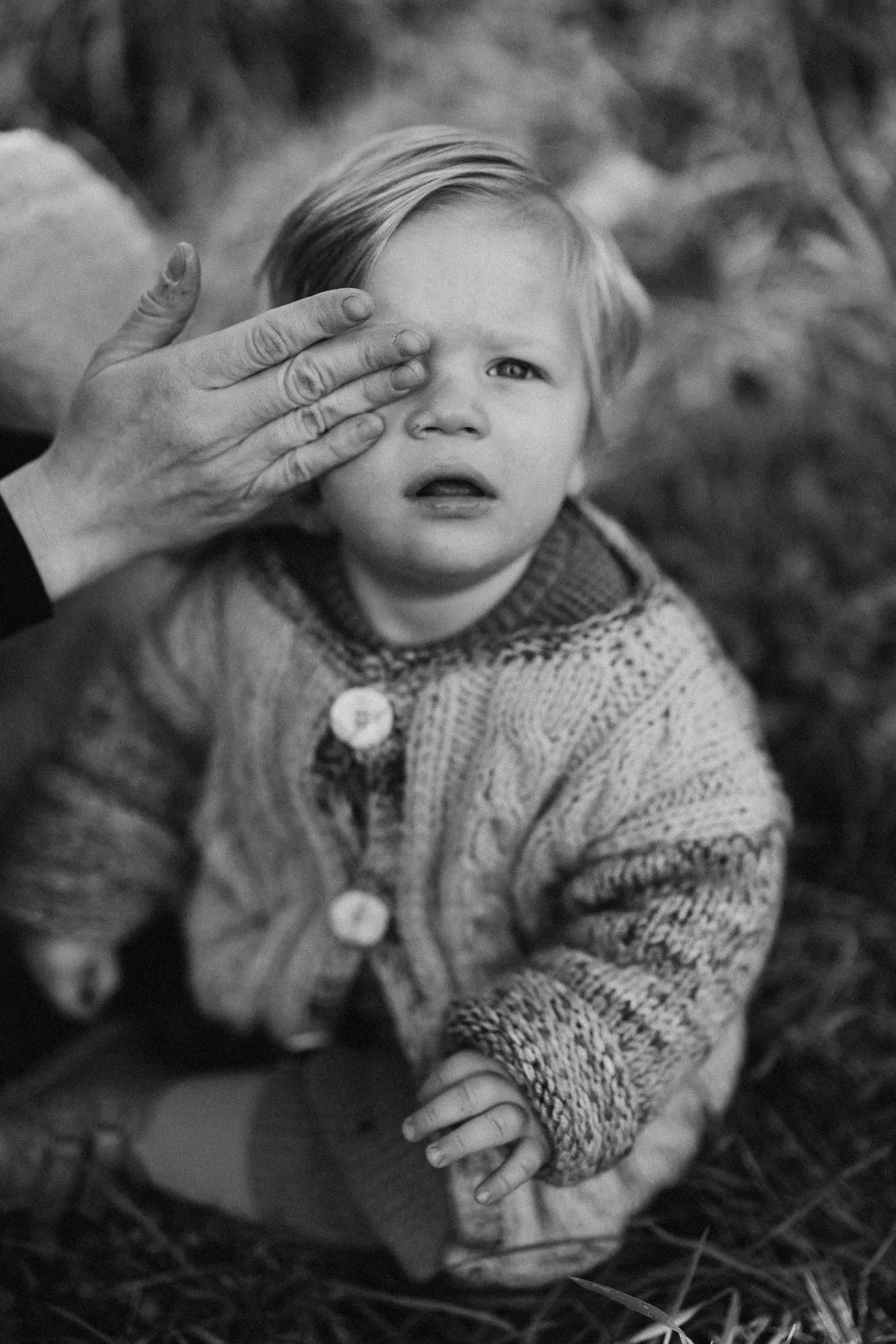 Small child in a knitted jumper, one hand on the face – family photography