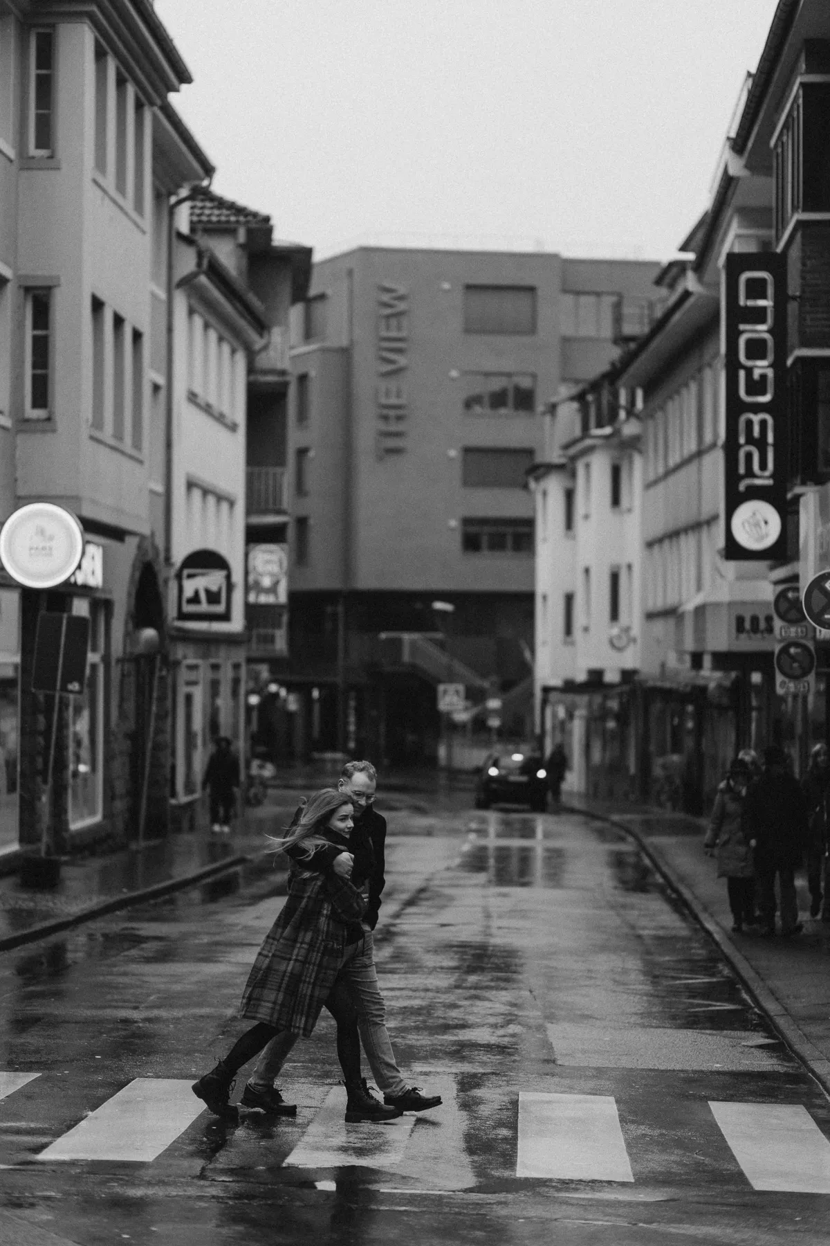 Paar überquert eine regennasse Straße in der Stadt