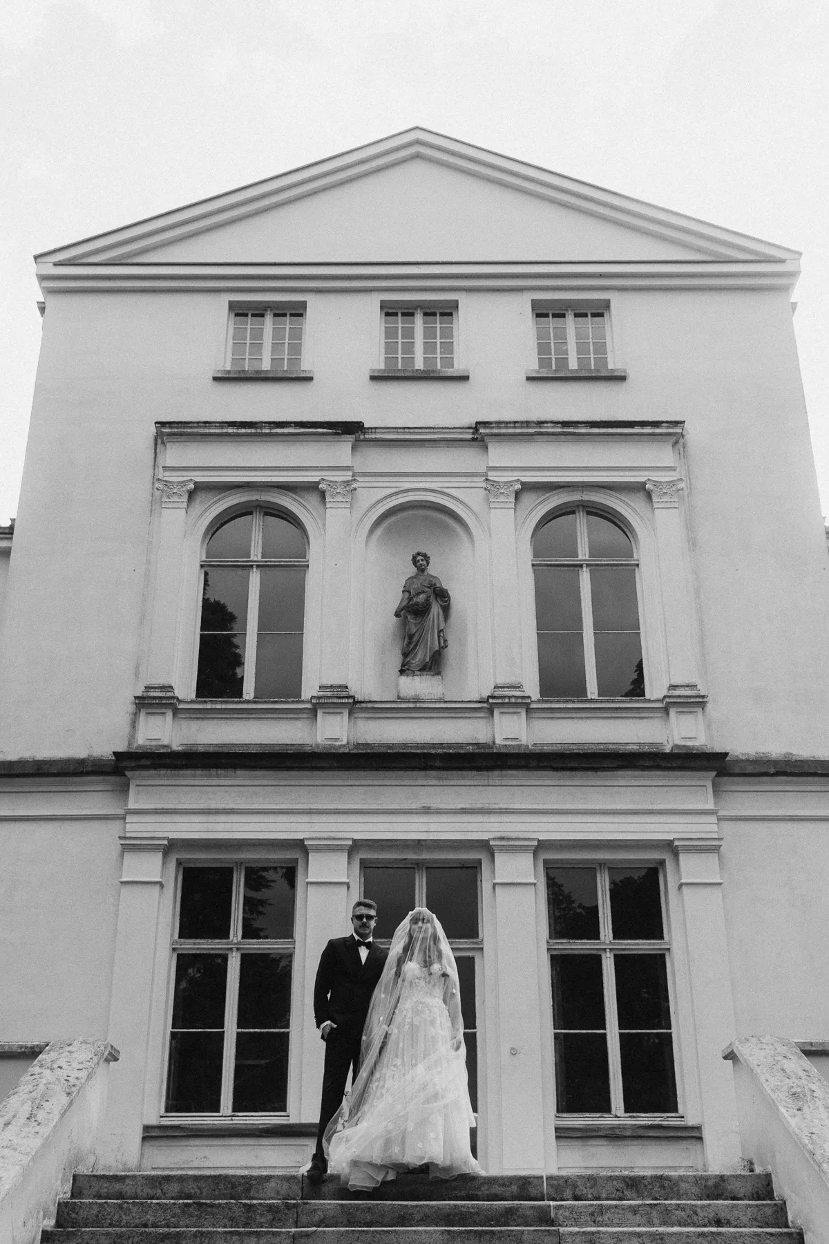 Brautpaar auf der Treppe vor einem weißen Herrenhaus, Schwarzweiß