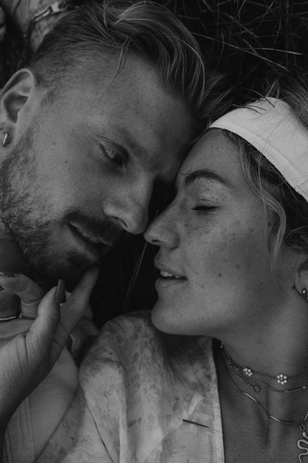 Couple lying cheek to cheek, black and white
