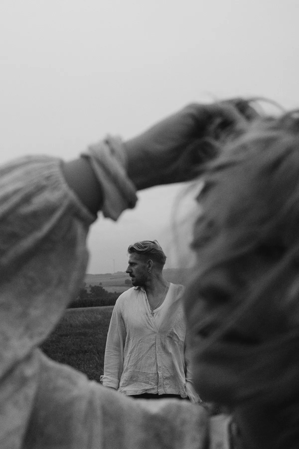 Couple in a field, the woman blurred in the foreground, black and white