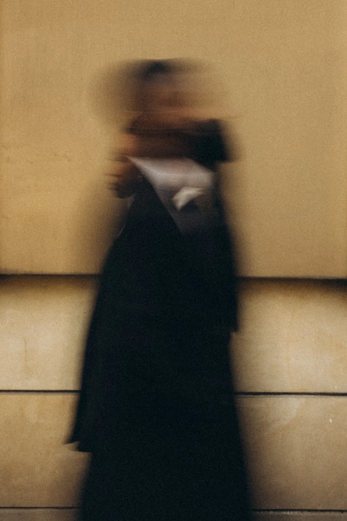 Woman in motion in front of a warm-toned wall, deliberately blurred