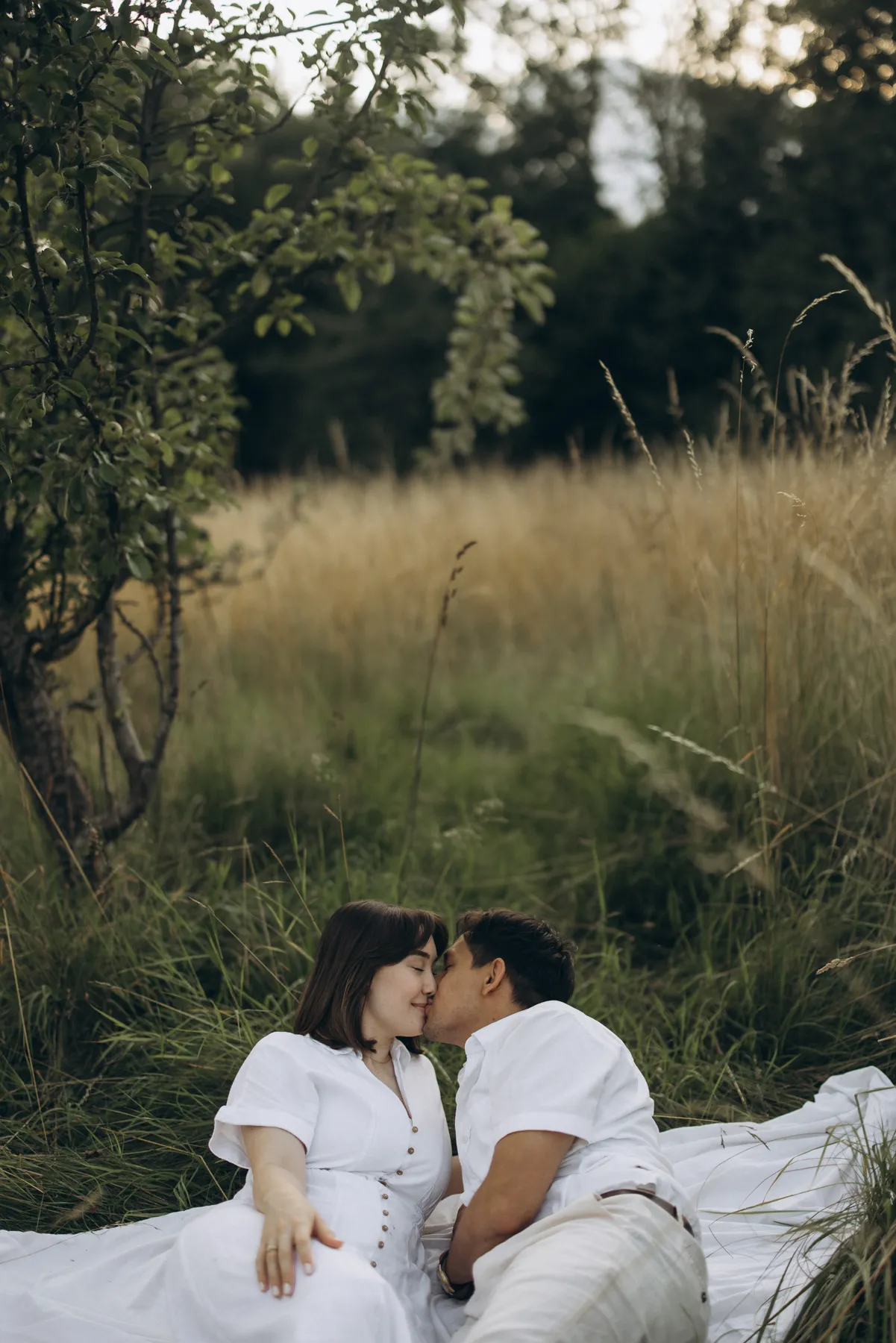 Couple kissing on a blanket in tall grass