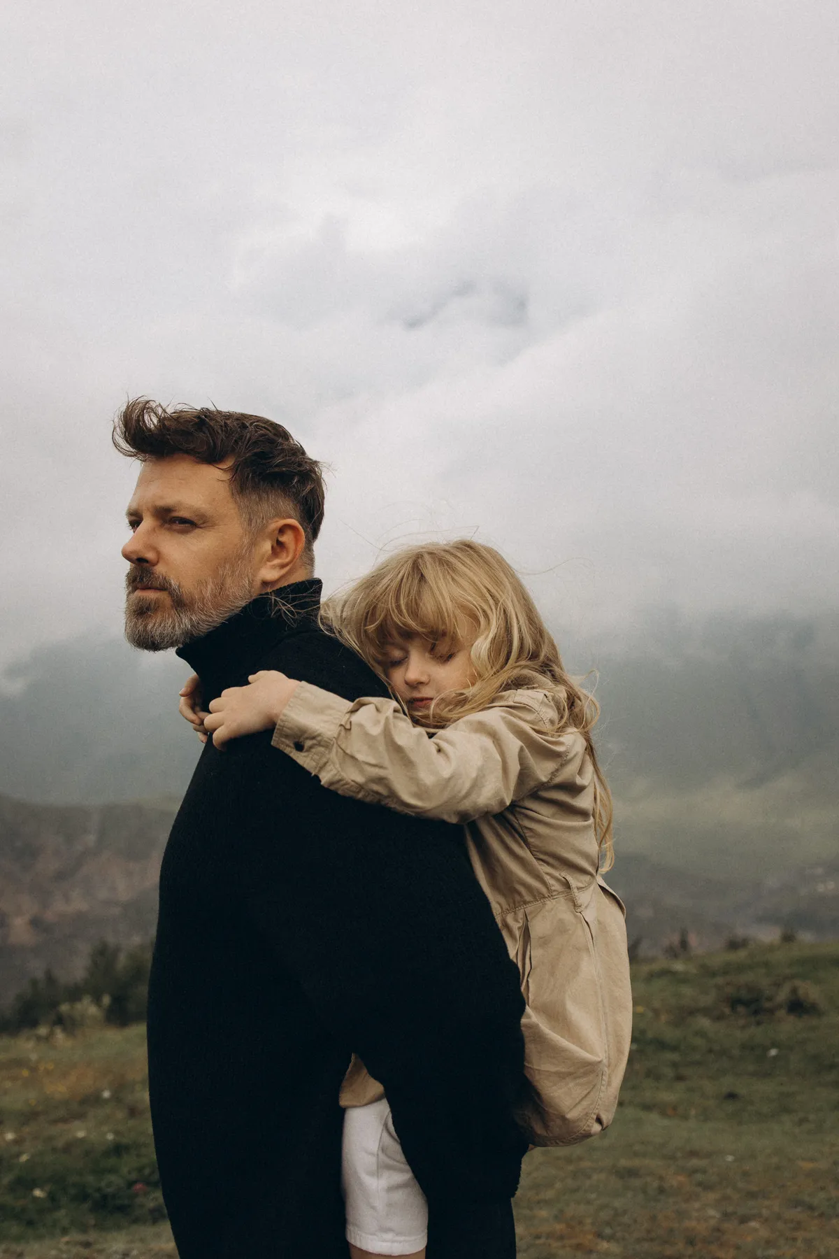 Father carries his daughter piggyback in the mountains