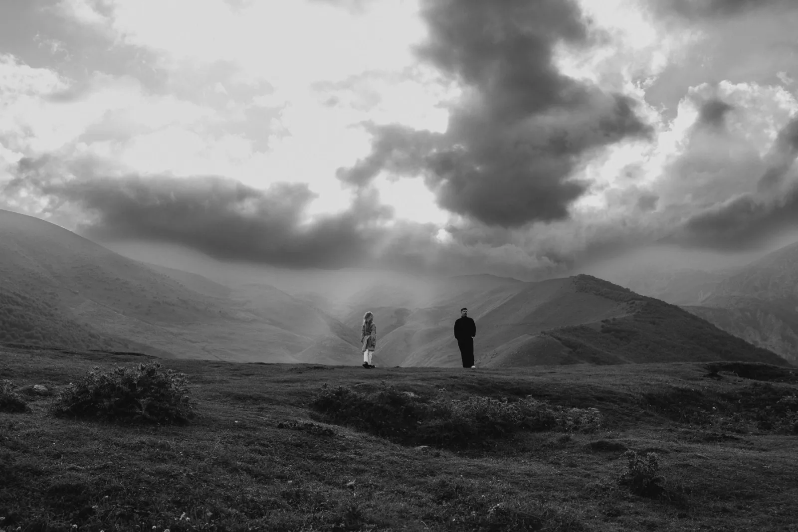 Father and daughter in a wide mountain landscape, black and white