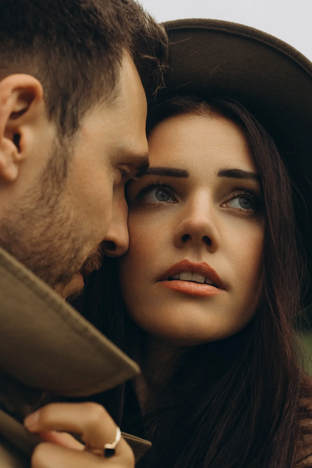 Couple cheek to cheek, she wears a hat