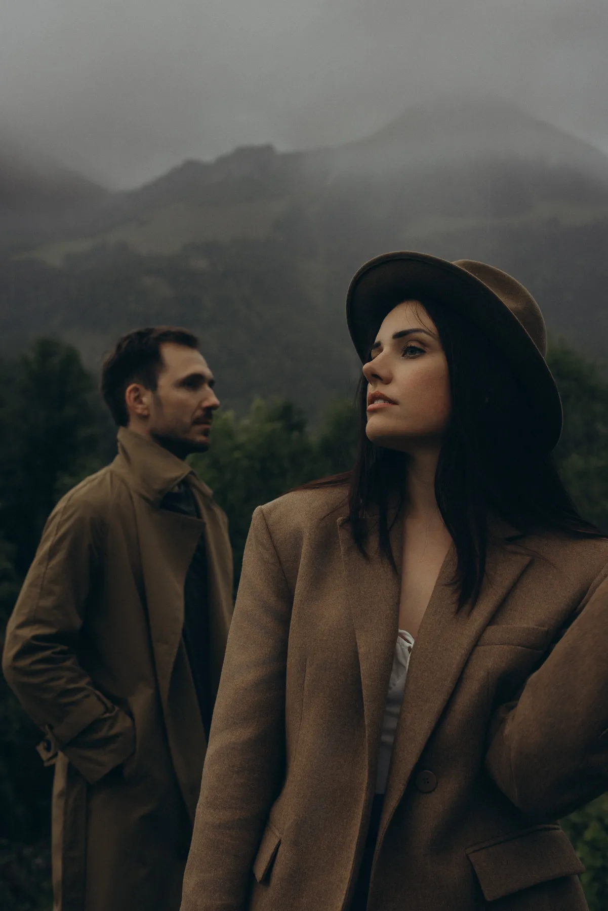 Couple in autumn coats in front of misty mountains