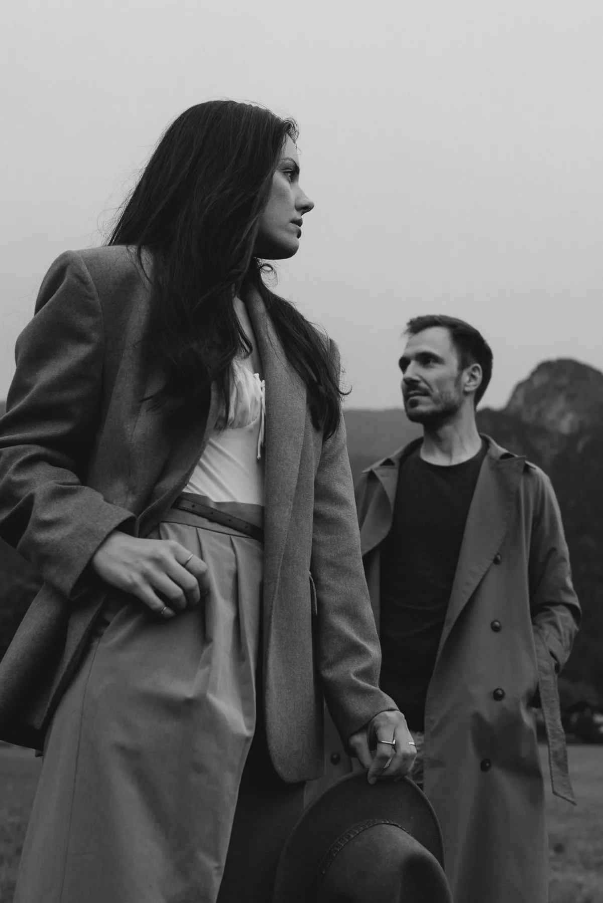 Couple in coats in front of mountains, black and white