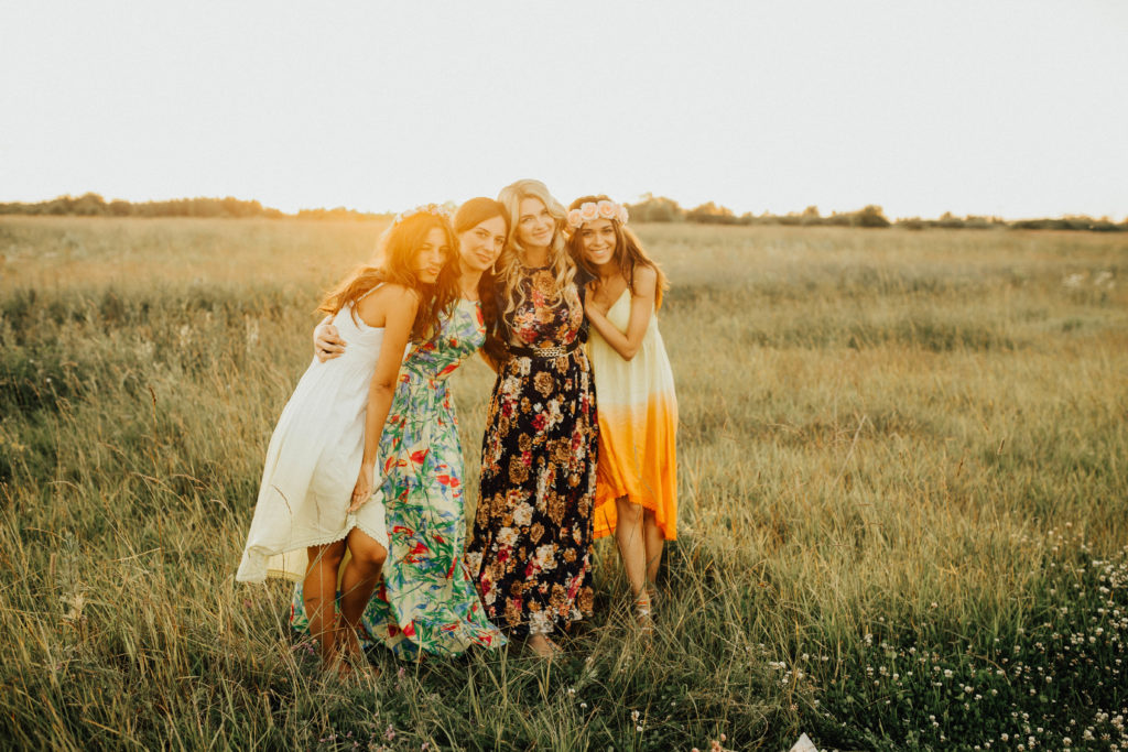 Foto von vier Frauen in Kleidern bei Sonnenuntergang auf einer Wiese